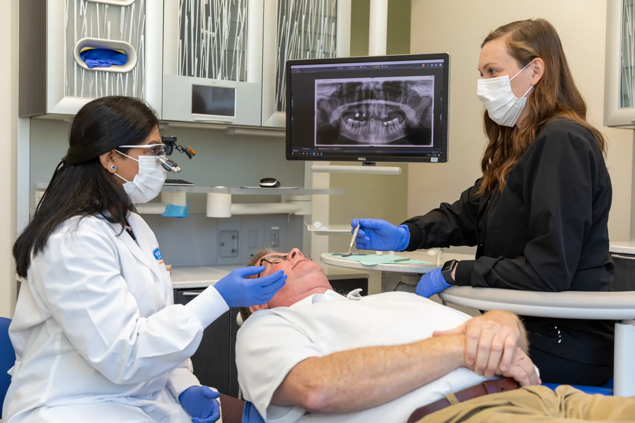 VSP Dental clinicians providing care with a patient as a dental X-ray appears on a monitor