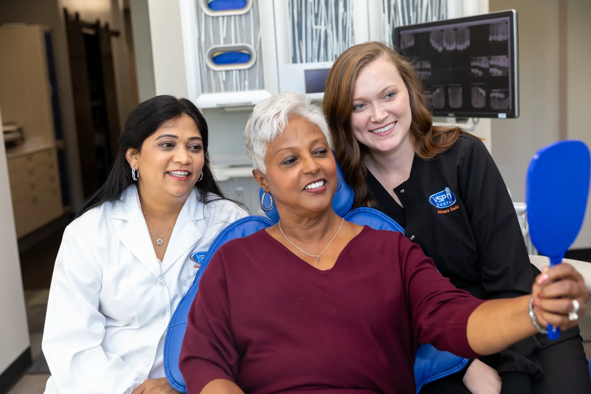 VSP Dental patient and team members reviewing her smile with a hand mirror