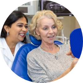 Danville Dentist Dr. Patel with mature woman checking her new smile with mirror